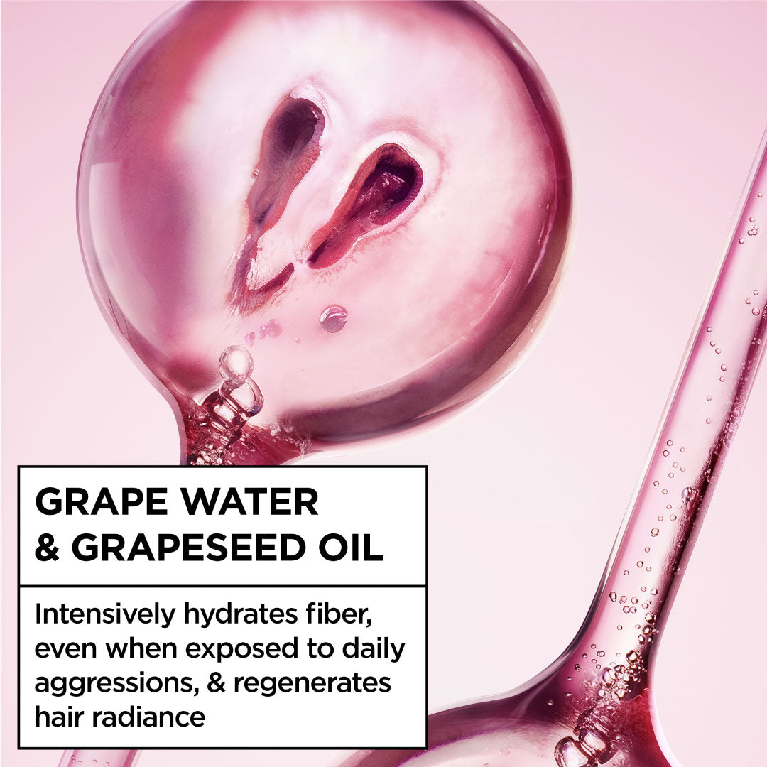 Grape water and grapeseed oil being poured into a glass with a pink background